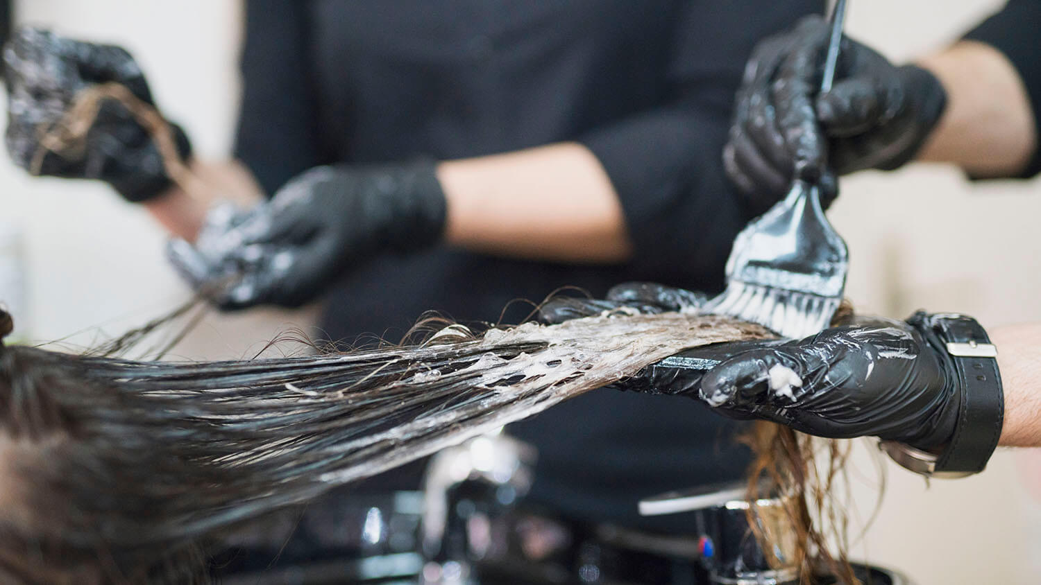 Chemicals being used on a woman's black hair.